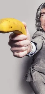 Man in a suit holding a banana like a weapon on a gray background.