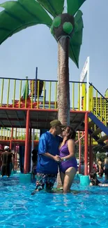 Couple enjoying summer fun at a vibrant water park with palm tree backdrop.