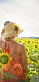 Woman in hat stands in a vibrant sunflower field under a clear sky.