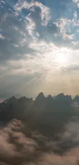 Mountain peaks with sunrays shining through clouds on a serene landscape.