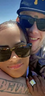 Couple smiling at the beach wearing sunglasses on a sunny day.