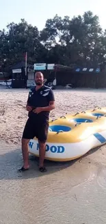 A person with a yellow inflatable raft on a sunny beach.