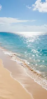 Sunlit beach with blue ocean waves under clear sky.