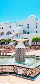 Mediterranean courtyard with fountain under a bright blue sky.