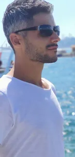 Man in sunglasses with ocean backdrop, sunny day.