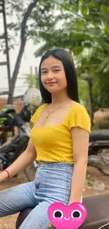 Woman in yellow shirt on motorcycle with green background.