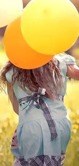 Child holding yellow balloons in a sunny field.