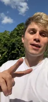 A young person taking a selfie outdoors on a sunny day under a blue sky.