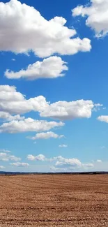 Blue sky with white clouds over a brown field.