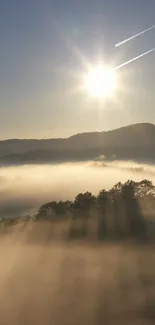 Sunlit misty mountains under a golden sunrise with fog.