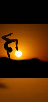 Acrobat silhouette balancing at sunset with orange sky.