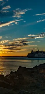 Sunset over ocean with silhouetted ship and vibrant sky.