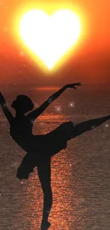 Ballerina silhouette with heart-shaped sun at sunset.