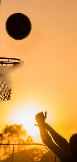 Silhouette of a basketball shot against a vibrant sunset sky.