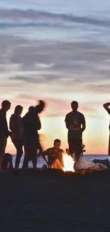 Silhouetted group at sunset beach bonfire under a twilight sky.