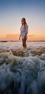 Sunset over the ocean with waves and a person standing on the beach.