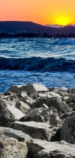 Sunset over ocean waves and rocky beach landscape.