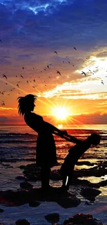 Silhouette of a woman and child at sunset on the beach, with birds in the sky.