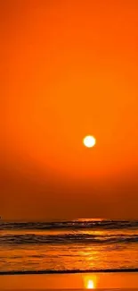 Silhouetted figure at sunset on beach with orange sky.