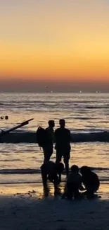 Silhouettes on a sunset beach with orange sky and calm ocean waves.