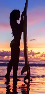 Silhouetted surfer at sunset on beach with vibrant sky.