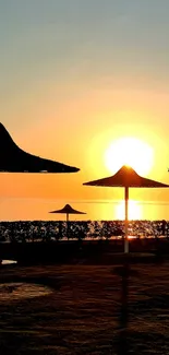 Silhouetted beach umbrellas at sunset over a calm sea.