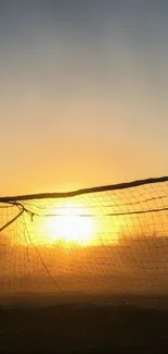 Soccer goal silhouette at sunset with golden glow.