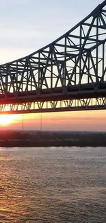 Sunset behind a bridge over a calm river, creating a serene silhouette.