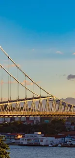 Scenic sunset bridge over calm water with city backdrop and vibrant sky hues.