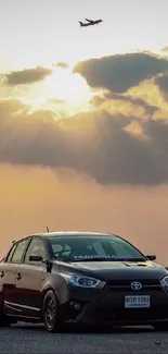 Car silhouette under a sunset sky with dramatic clouds and vibrant colors.