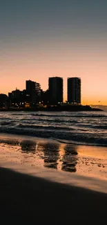 Sunset over city skyline with ocean waves and beach reflections.