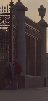 Sunset cityscape with ornate gate and people walking nearby.