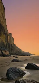 Serene sunset over a rocky beach, with towering cliffs and warm hues dominating the scene.