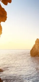 Serene sunset over a coastal landscape with rocky cliffs and ocean waves.