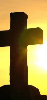 Silhouette of a cross against a vibrant yellow sunset.