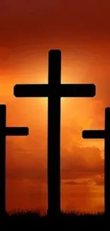 Silhouetted three crosses against a vibrant sunset sky, perfect for reflection.