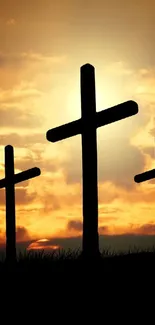 Silhouette of crosses against an orange sunset sky.