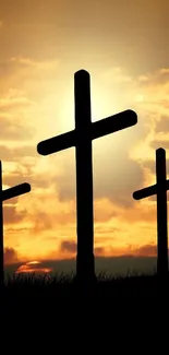 Three silhouetted crosses against a vibrant orange sunset sky.