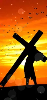 Silhouette of a cross against an orange sunset with birds flying.