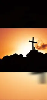 Silhouette of cross at sunset with vibrant orange and black colors.