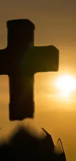 Silhouette of a cross at sunset with golden sky background.