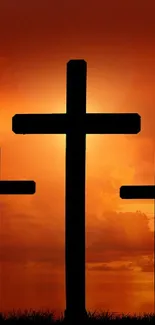 Three crosses against an orange sunset sky, creating a spiritual and serene atmosphere.