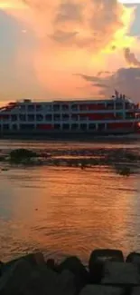 Cruise ship at sunset with vibrant orange sky and reflections on water.