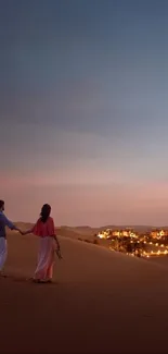 Couple walking in desert at sunset with glowing city lights.