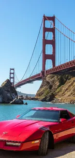 Red sports car in front of the Golden Gate Bridge under a clear blue sky.