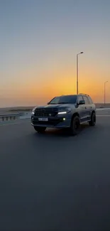 Car driving on empty highway at sunset, under orange sky.