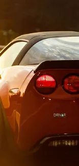 Red sports car driving on highway at sunset with vibrant scenery.