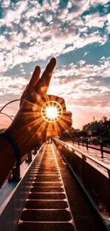 Artistic sunset reflection framed by a hand on a boardwalk.