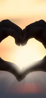 Heart-shaped hand silhouette at sunset with a glowing sky.
