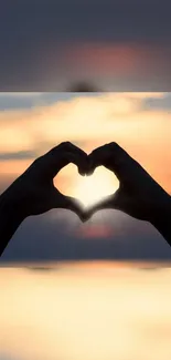 Silhouette of hands forming a heart at sunset, creating a warm, romantic scene.